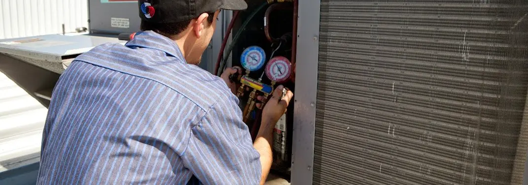 HVAC technician servicing a condenser unit in Sidney